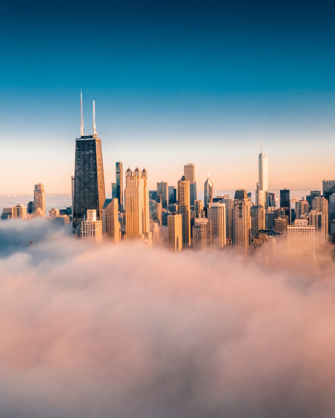 A city skyline rising above morning fog at golden hour